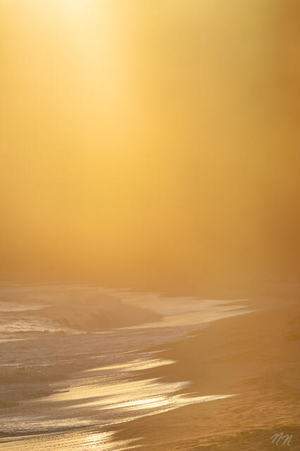 Golden light and ocean mist over Butterfly Beach in Montecito, California, with soft waves, glowing shoreline, and peaceful coastal atmosphere.