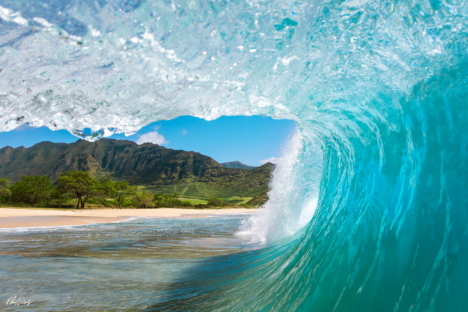 View in Paradise Turquoise ocean wave curling near a tropical beach with mountains in Oahu Hawaii.